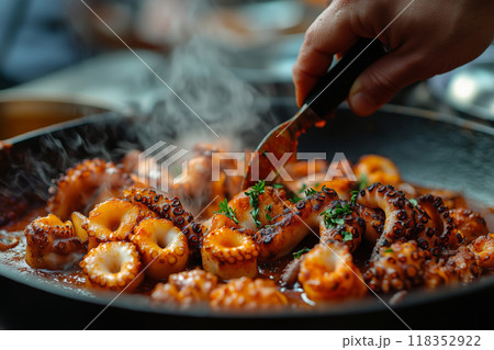 A chef skillfully seasons tender octopus with paprika, enhancing flavors in a vibrant culinary preparation 118352922
