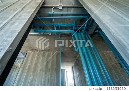 A bright blue pipes attached to a solid concrete wall A bright blue pipes attached to a solid concrete wall 118353980