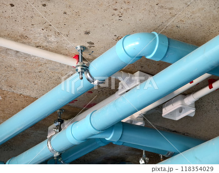 A bright blue pipes attached to a solid concrete wall A bright blue pipes attached to a solid concrete wall 118354029