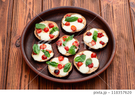 Italian mini pizza . Aubergine (eggplant ) with mozzarella cheese and basil . On rustic background Italian mini pizza . Aubergine (eggplant ) with mozzarella cheese and basil . On rustic background 118357620