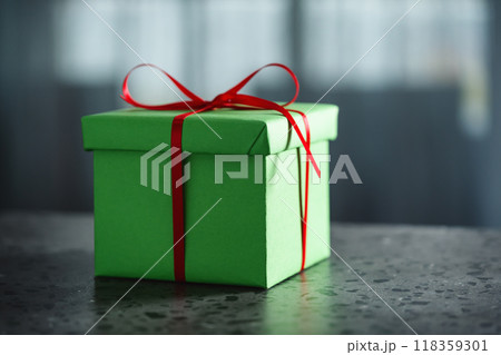 Green gift box with red ribbon against window on terrazo countertop with copy space Green gift box with red ribbon against window on terrazo countertop with copy space 118359301