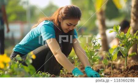 A group of young volunteers working together in a community gardening project. Focus on a smiling girl with gloves. Outdoor setting, teamwork, and environmental care concept A group of young volunteers working together in a community gardening project. Focus on a smiling girl with gloves. Outdoor setting, teamwork, and environmental care concept 118360286