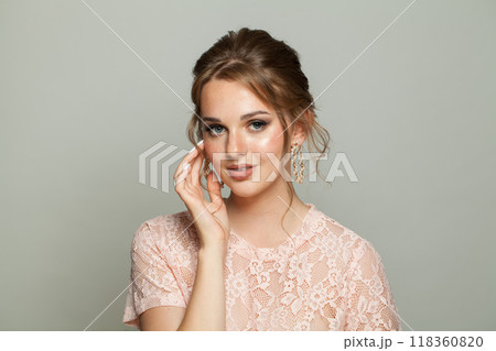 Positive glam woman fashion model with makeup and updo hairstyle on gray studio background 118360820