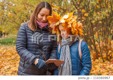 Portrait of mother and daughter holding smartphone in autumn park background 118360967