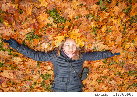 Autumn portrait of cheerful woman in fall yellow leaves wreath lying in fall leaves background Autumn portrait of cheerful woman in fall yellow leaves wreath lying in fall leaves background 118360969