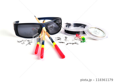Fishing accessories, blue glasses, floats and fishing line in the reel, stopper hooks and swivels with clasps on a white background, close-up, space for copyright Fishing accessories, blue glasses, floats and fishing line in the reel, stopper hooks and swivels with clasps on a white background, close-up, space for copyright 118361179