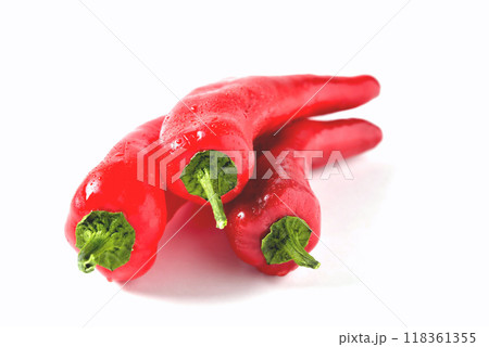 three red peppers of an elongated shape on a white background with drops of water, isolate 118361355