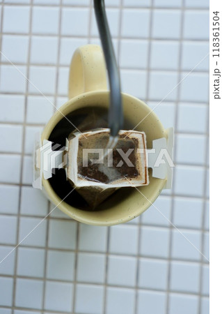 yellow cup freshly brewed coffee with convenient drip filter on table. prepare freshly brewed coffee 118361504