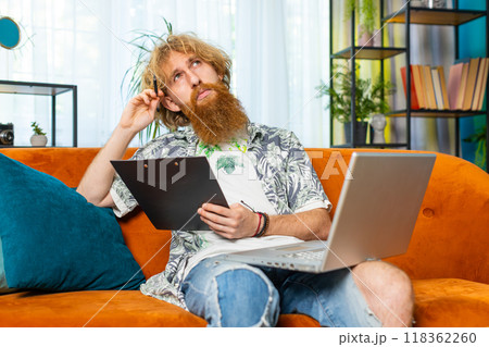 Young man freelancer work with documents from home, analyzing information prepare financial report Young man freelancer work with documents from home, analyzing information prepare financial report 118362260