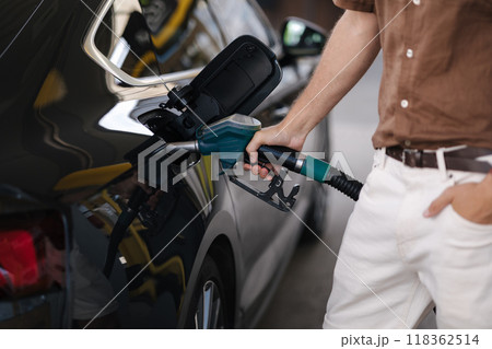 Close-up of human hand pumping gasoline car with fuel at the refuel station. Driver refueling the car at a gas station. Benzine. Fuel price increase 118362514