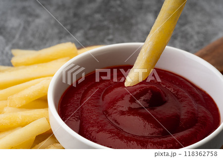 ケチャップにつけて食べるフライドポテトのクローズアップ 118362758