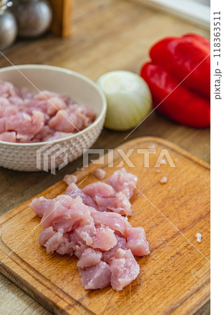 Pieces of fillet on a cutting board, onion and red pepper on the side 118363511
