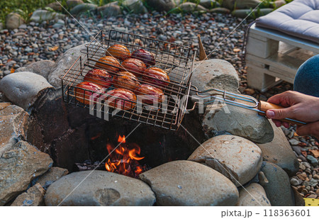 roasted peaches on open fire, caramelized texture on grill in female hands 118363601