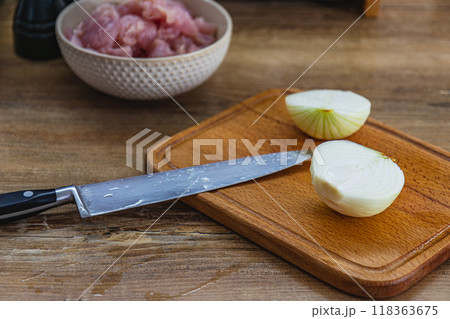 Onion cut into two parts on a board and a knife in the middle 118363675