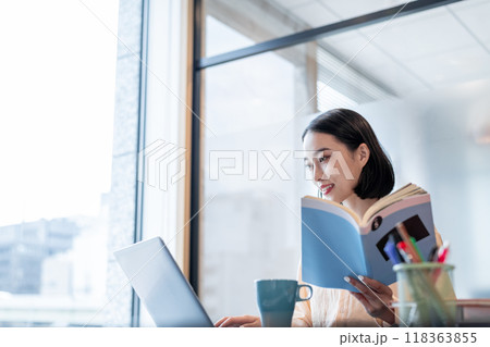 資料を片手にパソコンを操作している女性 資料を片手にパソコンを操作している女性 118363855