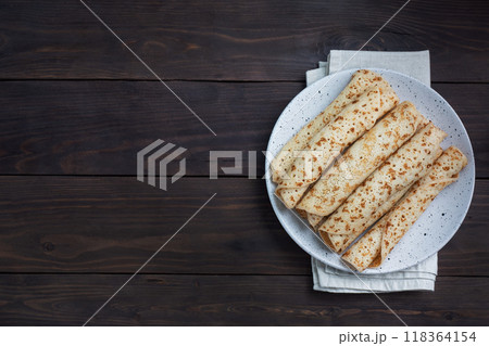 Thin pancakes rolled into a roll on a plate. The concept of a delicious breakfast or Maslenitsa. wooden background. copy space 118364154