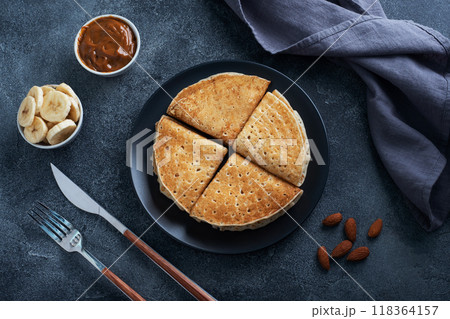 Pancakes with chocolate banana filling. Delicious breakfast of pancakes envelopes on a plate, dark concrete background. Pancakes with chocolate banana filling. Delicious breakfast of pancakes envelopes on a plate, dark concrete background. 118364157
