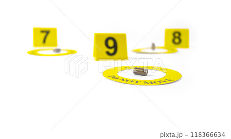 A spent bullet casing placed within a yellow circle, labeled with the text Evidence, Do Not Move, with a blurred number 9, 8 and 7 tag, set against a white background, concept of crime investigation. A spent bullet casing placed within a yellow circle, labeled with the text Evidence, Do Not Move, with a blurred number 9, 8 and 7 tag, set against a white background, concept of crime investigation. 118366634