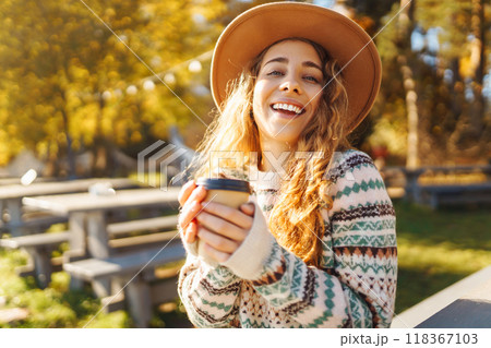 Fall concept woman drinking coffee on bench against backdrop of lake. Enjoying, solitude with nature 118367103