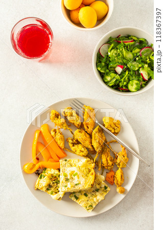 Enjoy a delicious vegetarian meal with fried zucchini flowers in batter, a cauliflower omelette with stewed peppers, and a fresh mixed green salad, perfect for breakfast or lunch 118367397