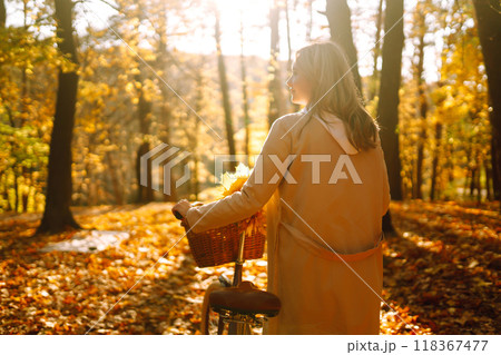 Stylish woman with a bicycle enjoying autumn weather in the park. Beautiful Woman in the autumn forest. Stylish woman with a bicycle enjoying autumn weather in the park. Beautiful Woman in the autumn forest. 118367477