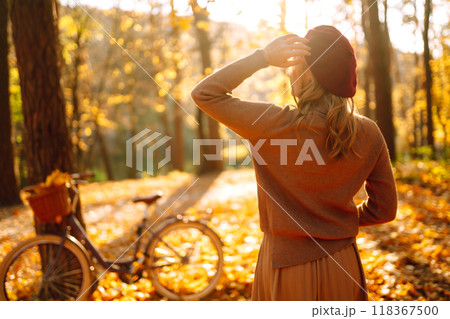 Stylish woman with a bicycle enjoying autumn weather in the park. Beautiful Woman in the autumn forest. Stylish woman with a bicycle enjoying autumn weather in the park. Beautiful Woman in the autumn forest. 118367500