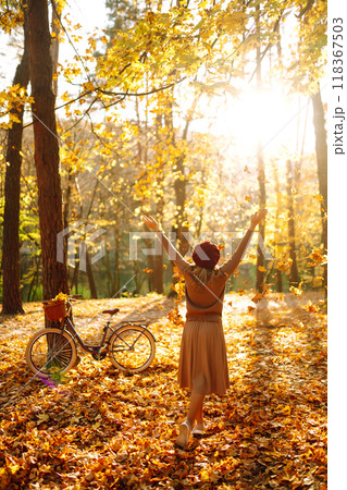 Beautiful Woman throws up autumn leaves and having fun in autumn park. Relaxation, enjoying. 118367503