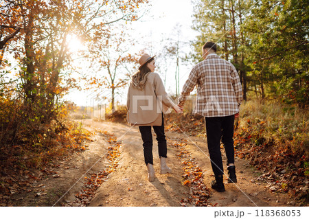 Happy couple in love newlyweds in casual clothes travel together, walk in autumn forest in nature. 118368053