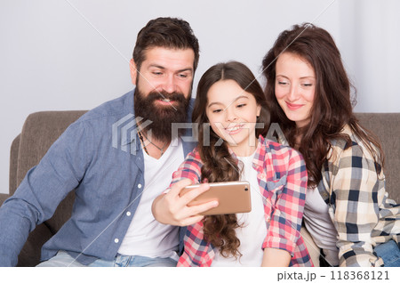 Family selfie. Family spend weekend together. Use smartphone for selfie. Friendly family having fun together. Mom dad and daughter relaxing on couch. Family posing for photo. Capture happy moments Family selfie. Family spend weekend together. Use smartphone for selfie. Friendly family having fun together. Mom dad and daughter relaxing on couch. Family posing for photo. Capture happy moments 118368121