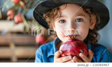 Adorable child with pomegranate and black hat in rustic setting 118368467
