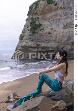 海を見て砂浜の岩に座る若い女性の人魚 118368568