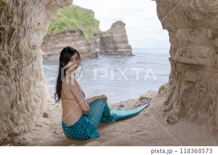 海が見える洞窟に座うぃ振り返る若い女性の人魚 118368573