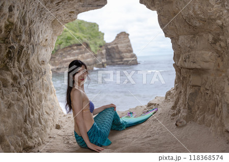 海が見える洞窟に座うぃ振り返る若い女性の人魚 118368574