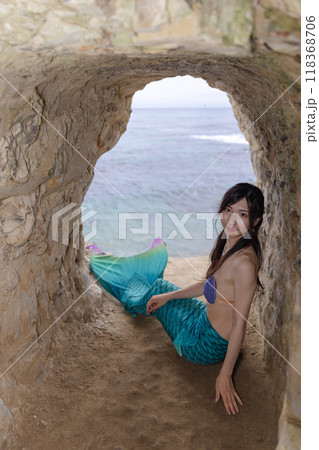 海が見える洞窟に座り振り返る若い女性の人魚 118368706