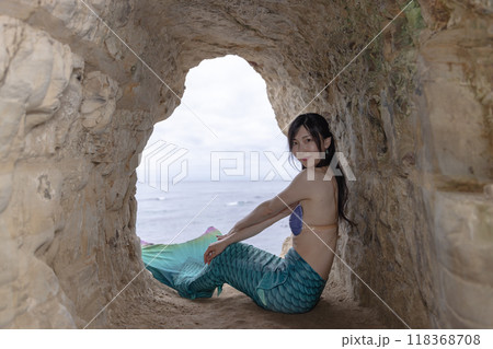 海が見える洞窟に座り振り返る若い女性の人魚 海が見える洞窟に座り振り返る若い女性の人魚 118368708