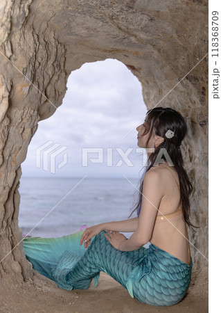 海が見える洞窟に座る若い女性の人魚 118368709
