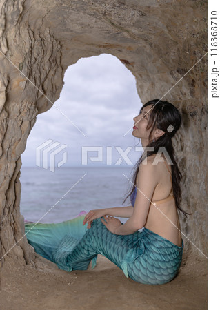 海が見える洞窟に座る若い女性の人魚 118368710