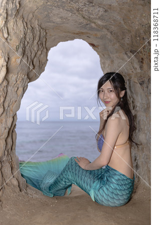 海が見える洞窟に座り振り返る若い女性の人魚 118368711