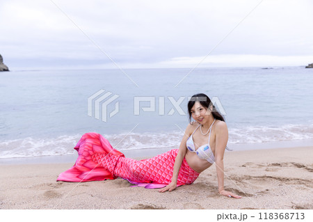 海の砂浜に座りこちらに目線を送る若い女性の人魚 118368713