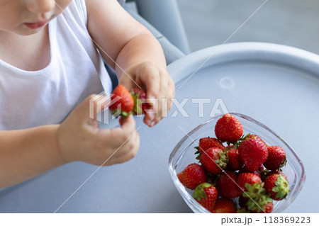 Little child taking strawberry from the plate. Little child taking strawberry from the plate. 118369223