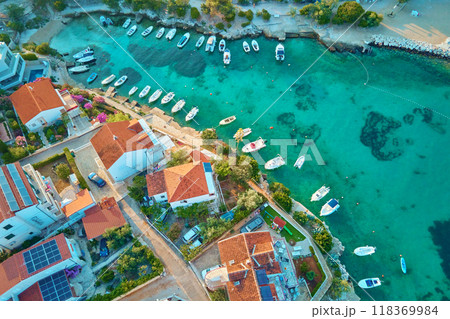 Birds eye view of sea coast with small town along seashore. Aerial top view of coastal village with red-roofed houses and boats near shore. Tourist town Rogoznica in Croatia on Adriatic Sea 118369984