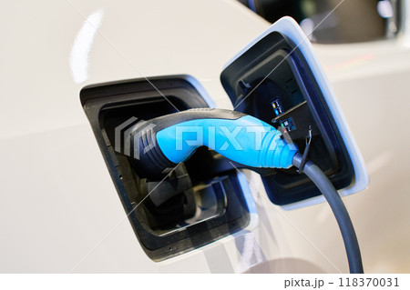 Close-up of electric vehicle charging at station. EV car with plugged-in cable recharging battery. Clean energy transportation 118370031