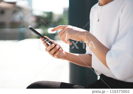 屋外でスマホを操作する女性の手元 屋外でスマホを操作する女性の手元 118373002