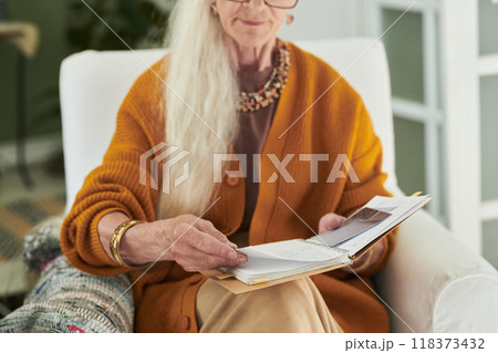Elderly Woman Reading Book While Sitting in Comfortable Chair Elderly Woman Reading Book While Sitting in Comfortable Chair 118373432