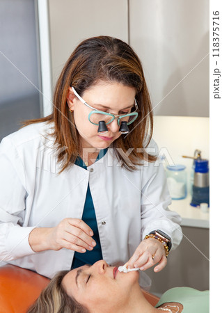 Dermatologist making a routine checkup on a senior famale patient using a binocular loupe. Dermatologist making a routine checkup on a senior famale patient using a binocular loupe. 118375716