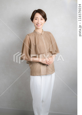 秋っぽいイメージの服の前ボケが美しい笑顔のミドル女性　縦 118376034