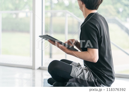 タブレット端末を使うスポーツウェア姿の若いアジア人男性 118376392