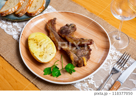 Grilled lamb spare ribs with baked potatoes garnished with greens 118377050