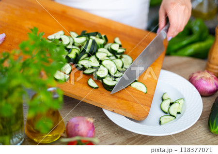 Female hands cuts vegetables on cutting board Female hands cuts vegetables on cutting board 118377071