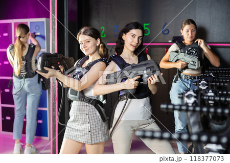 Two cheerful and happy girls friends pose in locker room before laser tag match. 118377073